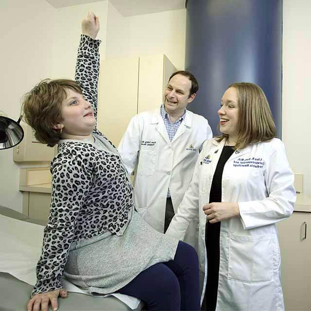Neurologists Lisa Sun and Ryan Felling standing next to a girl who is recovering from stroke